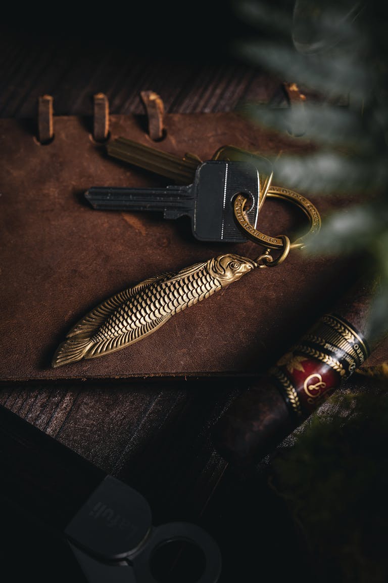 A rustic still life composition featuring keys, a keychain, and a cigar on a wooden surface.