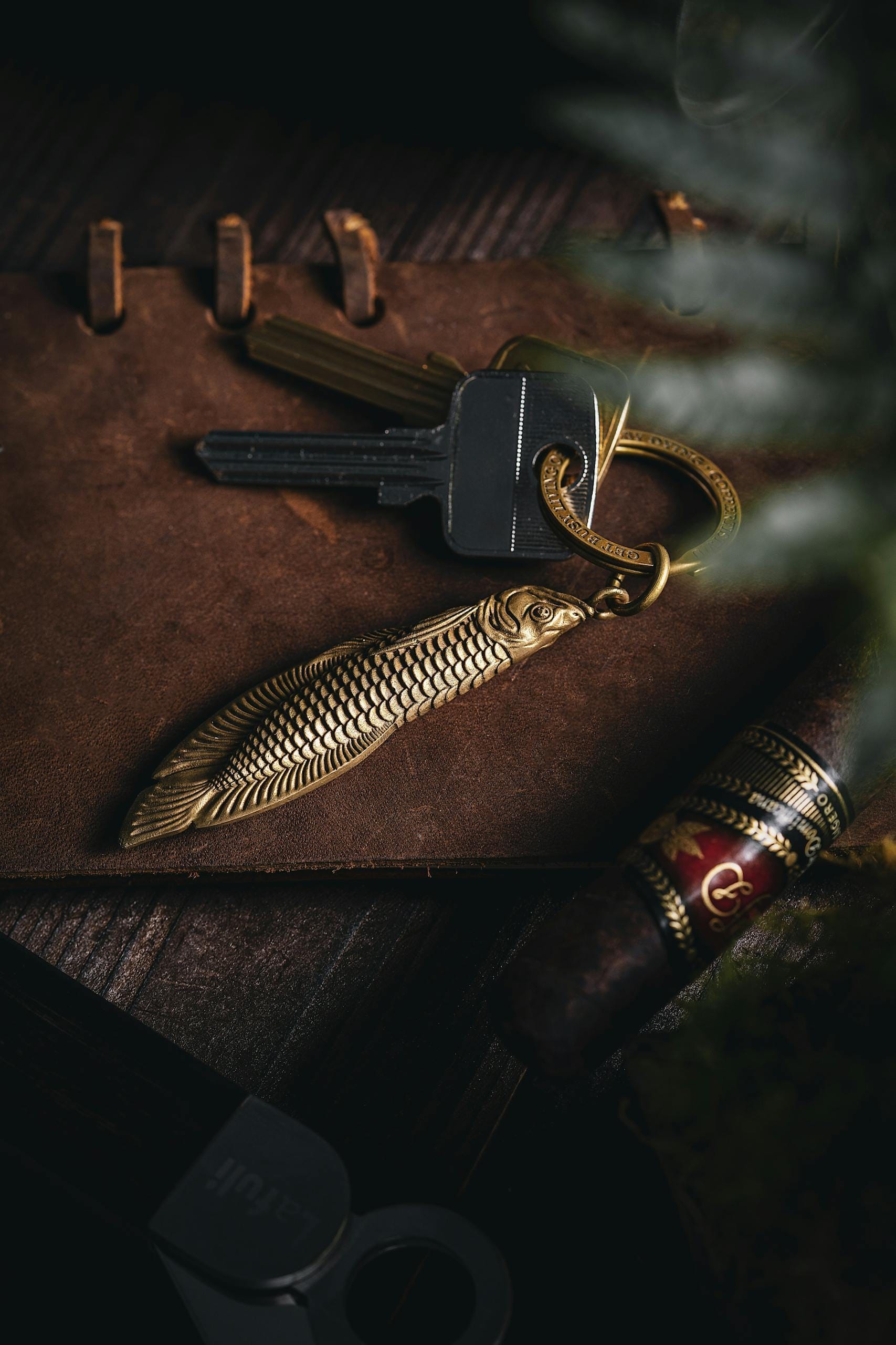 A rustic still life composition featuring keys, a keychain, and a cigar on a wooden surface.