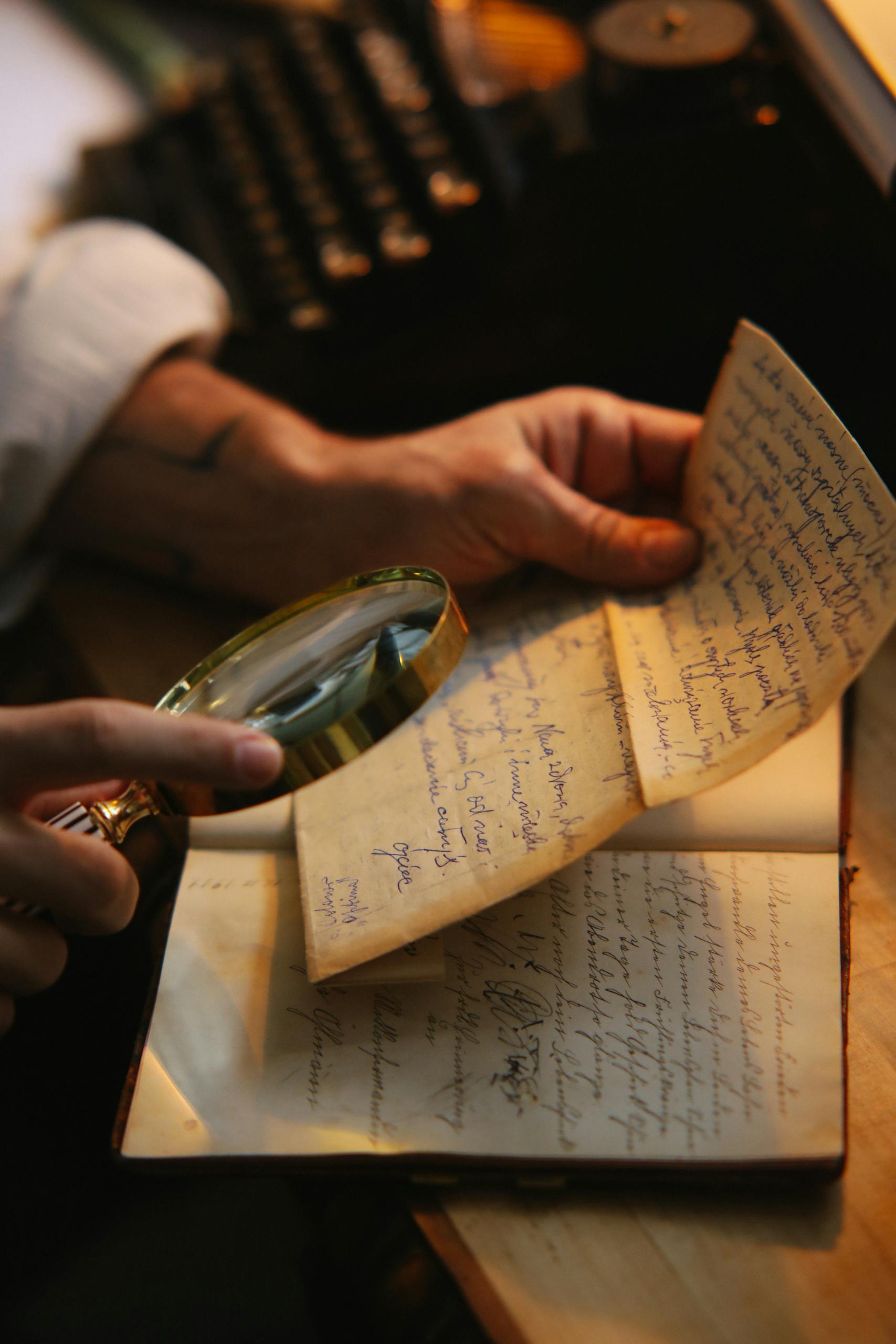 Close-up of a person inspecting a vintage handwritten letter with a magnifying glass.