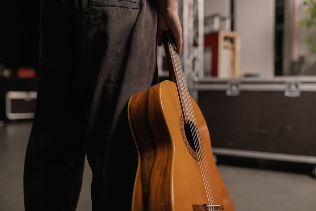 Una persona sosteniendo una guitarra acústica. Los unplugged son conciertos ejemplo de modos contractuales.